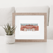 Load image into Gallery viewer, A colour print of Aston Villa Football Stadium, the piece is in a wooden frame on a coffee table beside a small succulent.

