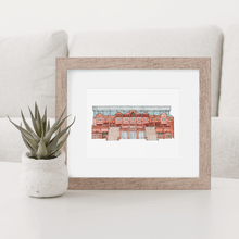 Load image into Gallery viewer, A colour print of Aston Villa Football Stadium, the piece is in a wooden frame on a coffee table beside a small succulent.