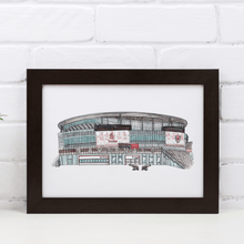 Load image into Gallery viewer, A framed print of the Emirates Stadium, showing the front of the Arsenal FC ground. The print is in a white frame against a white brick wall, on a white table.