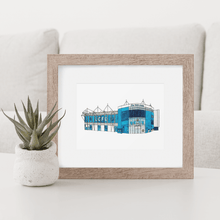 Load image into Gallery viewer, A framed print of Leicester City Football Stadium. A detailed, full colour illustration of the football ground. Photographed in a wooden frame on a white table.