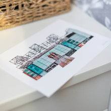 Load image into Gallery viewer, A hand drawn and painted illustration of Manchester United's football stadium. The piece is drawn and painted in pen and watercolours, it is sat on a white bedside table.