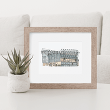 Load image into Gallery viewer, A Newcastle United football stadium print, the print shows St. James' Park, home to Newcastle United F.C. It's in a white frame, on a white coffee table.
