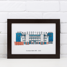 Load image into Gallery viewer, A personalised Everton football ground print, with the words &#39;Goodison Park 1892-2023&#39; printed underneath. It is in a white frame against a white brick wall.
