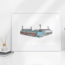Load image into Gallery viewer, A detailed illustration of the Portman Road football stadium where Ipswich Town Football Club play. Printed from Jessica Sian's hand drawn artworks. The piece is in a white frame on a white table.