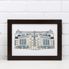 Load image into Gallery viewer, A framed A4 Chelsea Football print, a detailed illustration of the stadium. Framed in a black frame, the frame is propped against a white brick wall.
