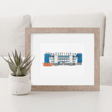 Load image into Gallery viewer, A detailed print of Goodison Park, home to Everton Football Club. The print is framed in a simple wood frame and photographed on a white coffee table.
