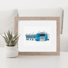 Load image into Gallery viewer, A framed print of Leicester City Football Stadium. A detailed, full colour illustration of the football ground. Photographed in a wooden frame on a white table. 
