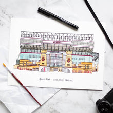 Load image into Gallery viewer, A hand drawn and painted print of West Ham United&#39;s Boleyn Ground. The piece is on a desk with a paintbrush and pen.
